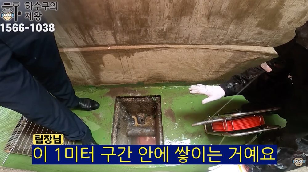 광진구 군자동 카페 하수구 막힘 현장에서 작업자가 집수정과 배관 구간을 가리키며 약 1미터 구간에 오염물이 쌓인 원인을 설명하는 장면