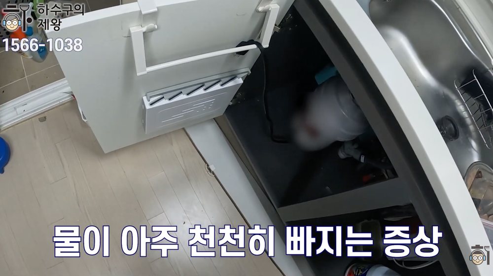 싱크대 하부장을 열고 주방 배관 점검을 진행하며 물이 느리게 빠지는 증상을 확인하는 장면