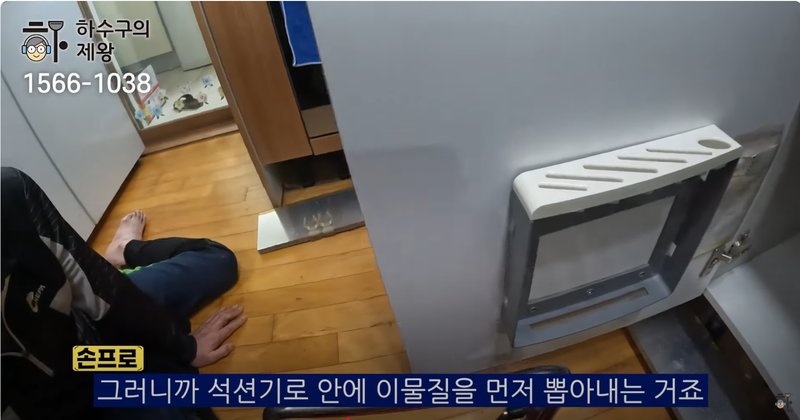 부천 상동 아파트 싱크대 하수구에서 손으로 이물질을 제거하는 작업 장면