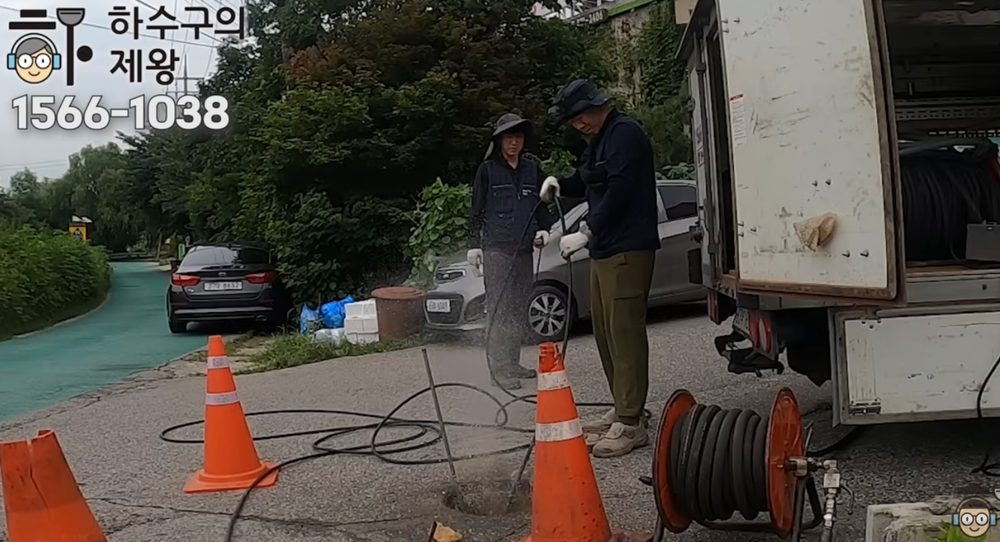 의정부 용현동 요양원 외부 맨홀에서 고압 세척 장비로 배관 기름 슬러지를 제거하는 작업 현장