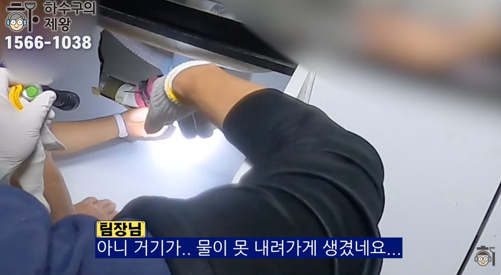광진구 구의동 빌라 싱크대 하부 배관 점검 중 물이 원활히 내려가지 않는 배수 막힘 증상을 확인하는 현장 이미지