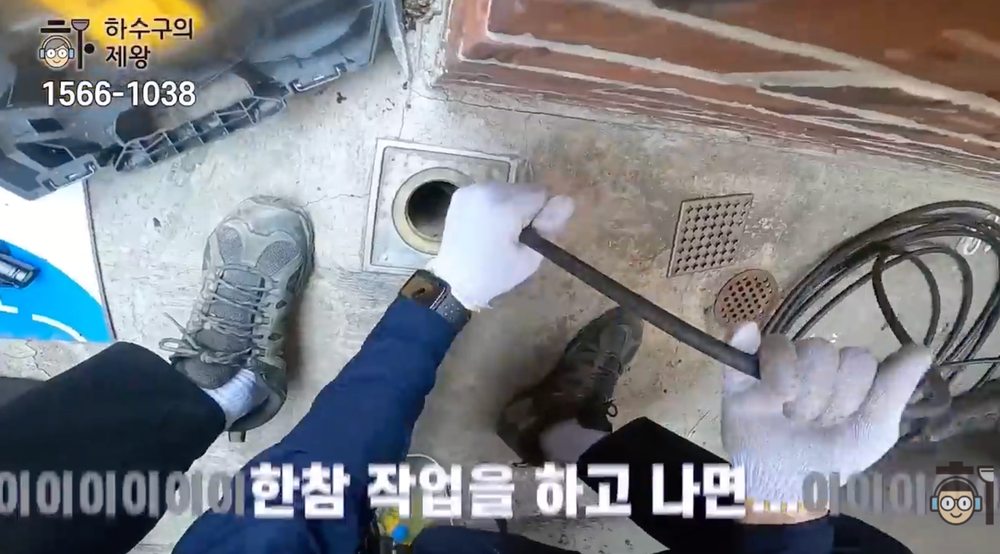 송파구 풍납동 빌라 주방 하수구 배관에 샤프트 장비를 투입해 기름 슬러지와 이물질을 제거하는 작업 장면