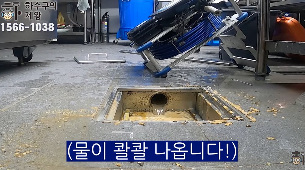 식당 주방 바닥 트렌치 배수구에서 작업 후 물이 콸콸 빠지며 역류 없이 배수 상태를 확인하는 장면