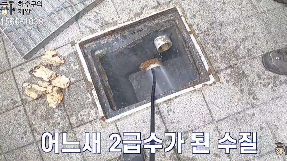 마포구 성산동 빌라 주차장 하수구 막힘 현장에서 외부 집수정 쪽으로 고압세척 장비를 투입해 배관 내부 침전물과 오염수를 강하게 세척하는 작업 장면