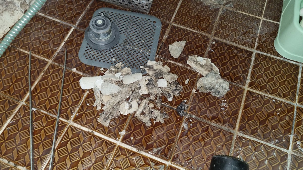 일산 화장실 하수구 청소 현장, 플렉스샤프트로 제거된 석회 찌꺼기와 오염물이 바닥에 모여 있는 모습