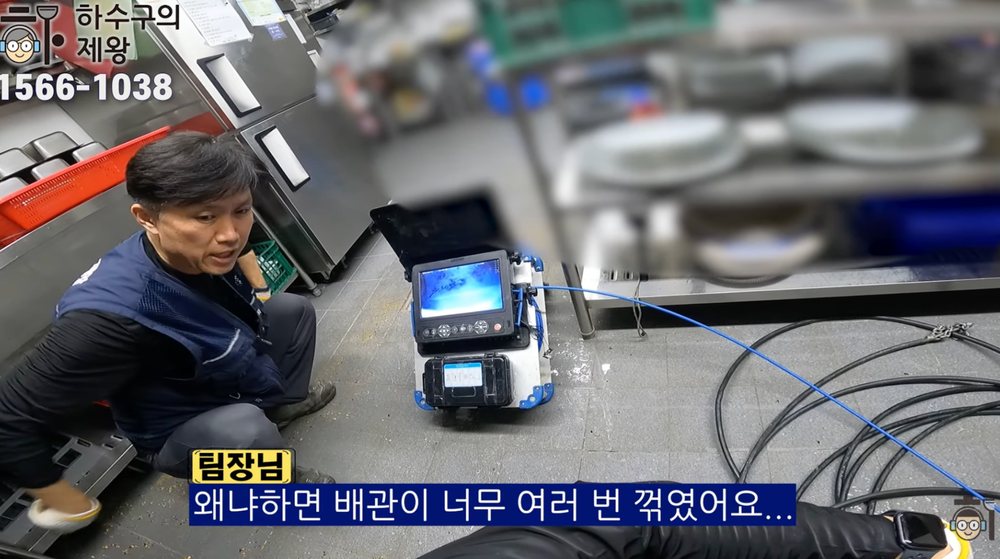 작업자가 내시경 장비 옆에서 식당 주방 하수구 배관이 여러 번 꺾여 막힘이 생긴 이유를 설명하는 장면