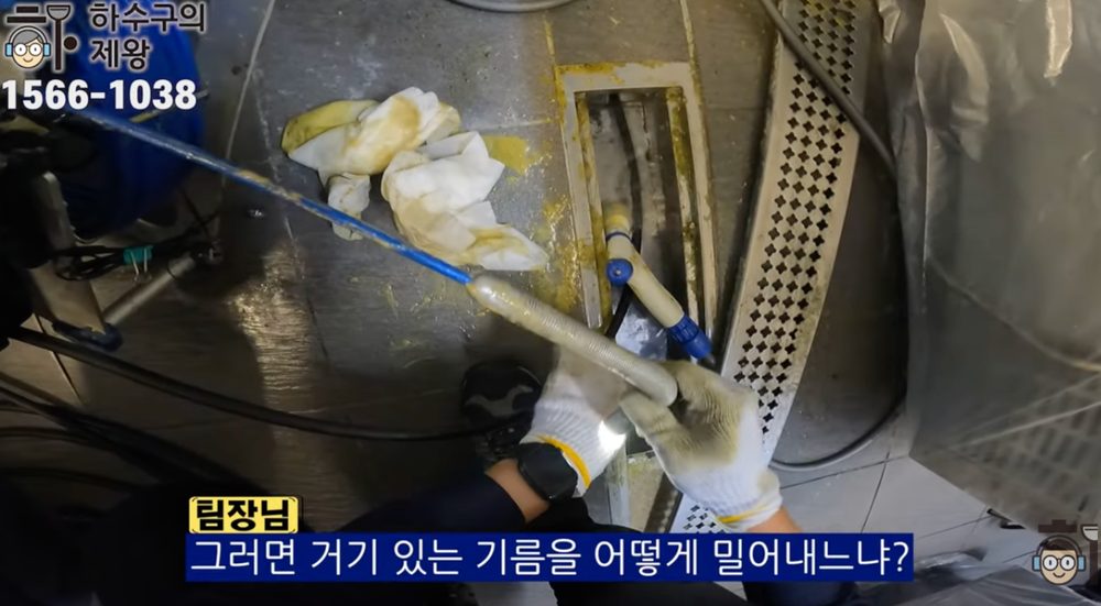 마포구 합정동 식당 하수구 막힘 현장에서 작업자가 주방 트렌치 배관과 기름 슬러지 원인을 설명하며 배관 관리 방법을 안내하는 장면