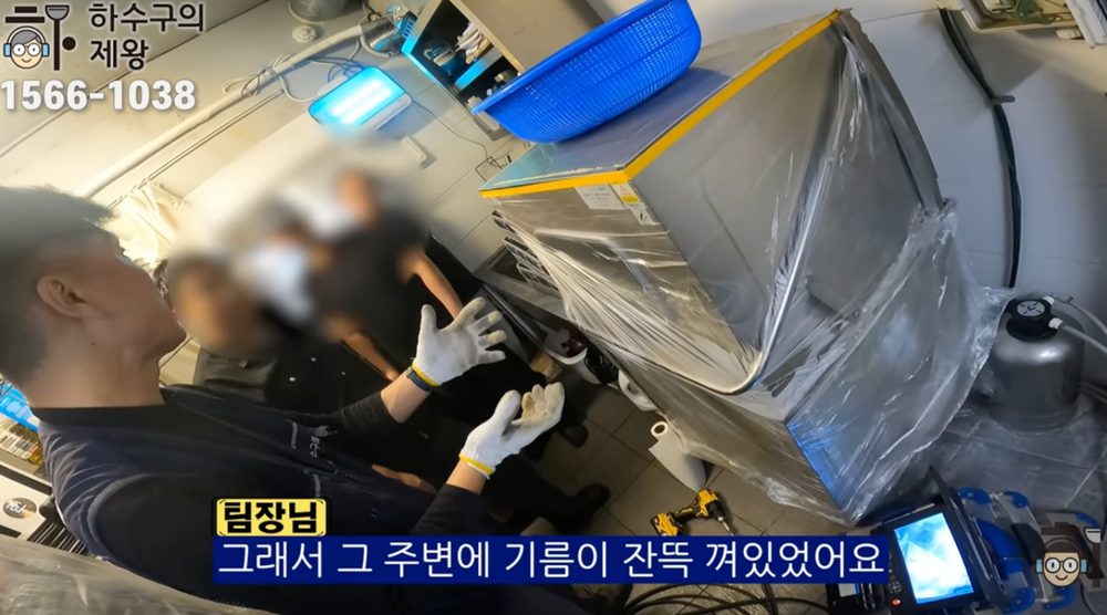 마포구 합정동 식당 주방 하수구 역류 현장에서 작업자가 기름 슬러지와 배관 내부 오염 원인을 고객에게 설명하는 모습