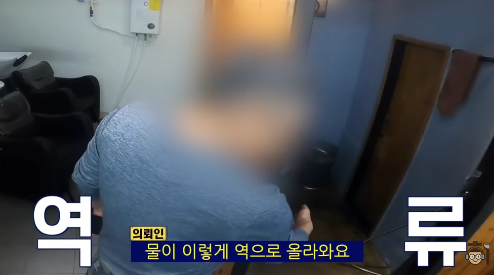 바닥 배수구에서 물이 역류하는 문제를 확인하는 장면