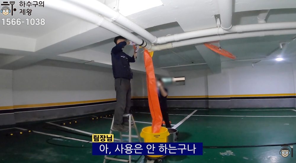 마포구 성산동 빌라 주차장 하수구 막힘 현장에서 천장 배관 작업 전 보양을 설치하고 오염수 유도 호스를 연결해 점검 준비를 하는 모습