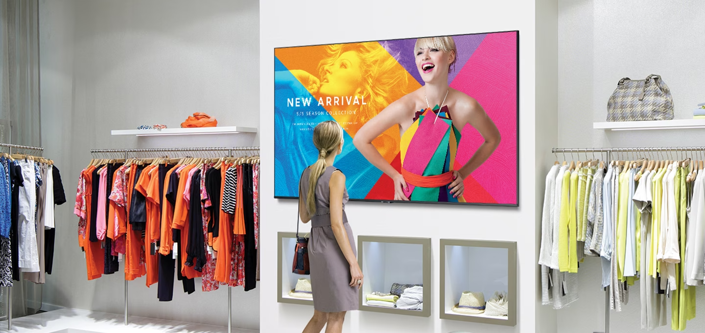 백화점 매장에 여성이 벽에 설치된 사이니지를 보고 있습니다.