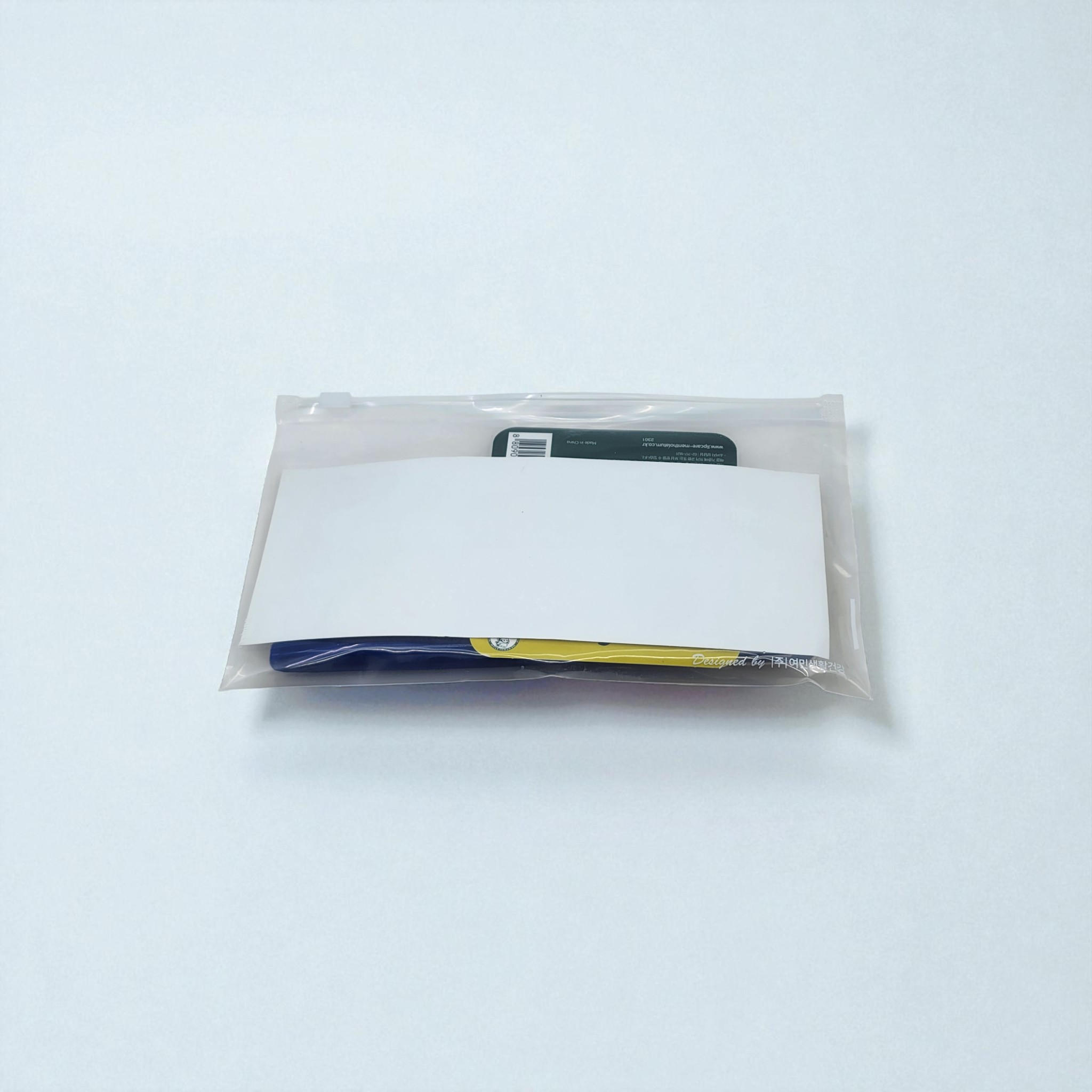 케어 세트가 담긴 지퍼 파우치의 뒷면. 로고 인쇄가 가능한 넓은 흰색 라벨이 부착되어 있습니다.