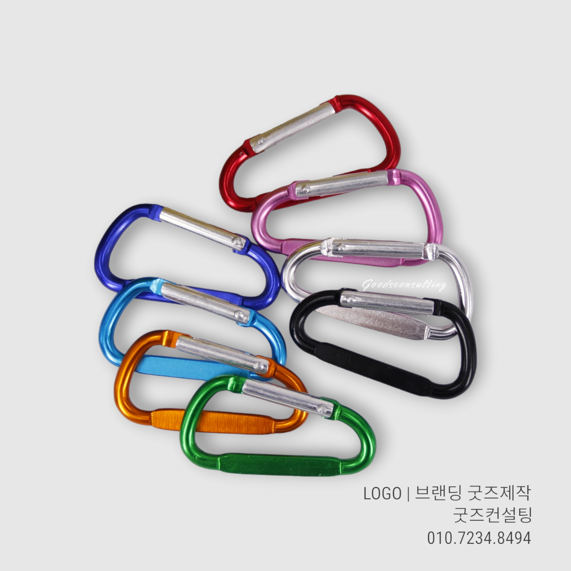 다양한 색상의 D형 미니 카라비너에 로고 각인 제작을 준비하는 이미지. 블랙, 블루, 레드, 그린, 실버, 핑크 등 여러 컬러의 판촉용 알루미늄 카라비너가 모여 있음