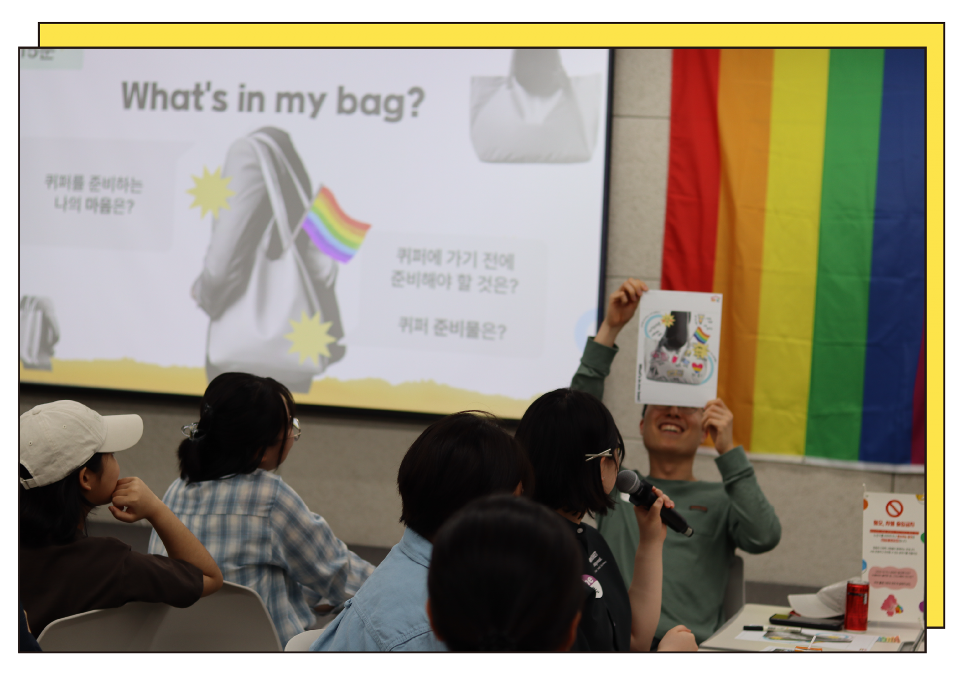 A participant presenting while holding a sheet of paper at a pre-workshop for a queer culture festival.