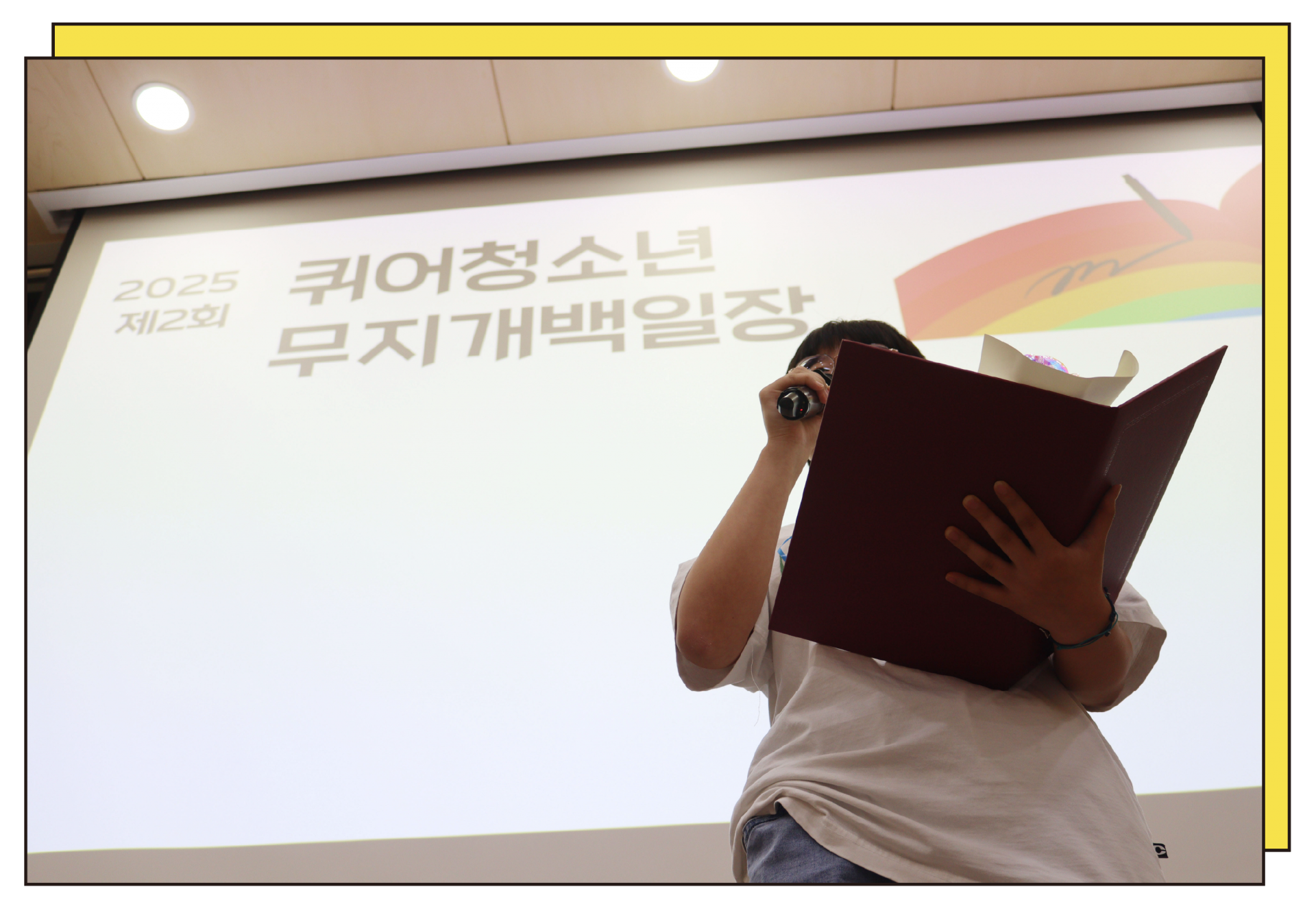 An LGBTQ+ youth delivering an acceptance speech at the Queer Youth Rainbow Writing Contest awards ceremony.