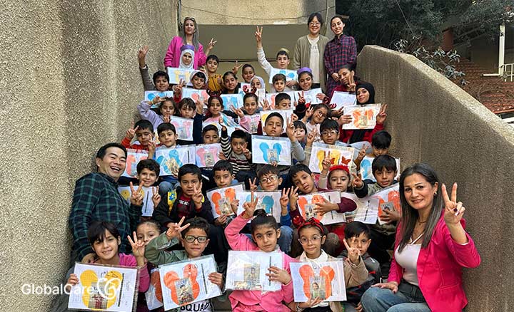 각자의 사진을 들고 웃고 있는 난민 어린이들과 교사들