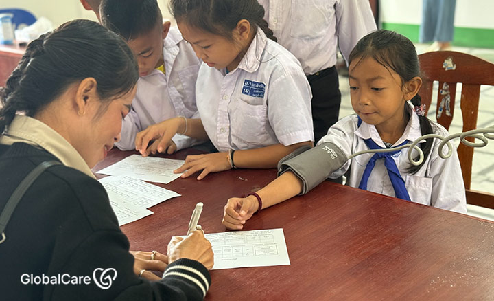 어린이의 혈압을 재고 기록지에 작성하고 있는 현지 직원