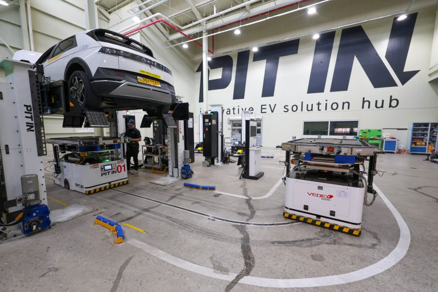 지난달 29일 경기도 안양시 '피트인'에 전기 택시 아이오닉 5가 배터리 교체를 위해 리프트에 올라가 있다. 로봇 한 대(우측)가 다 쓴 배터리를 싣고 나오고 있고, 다른 로봇은 차량 아래쪽에서 완전히 충전된 배터리