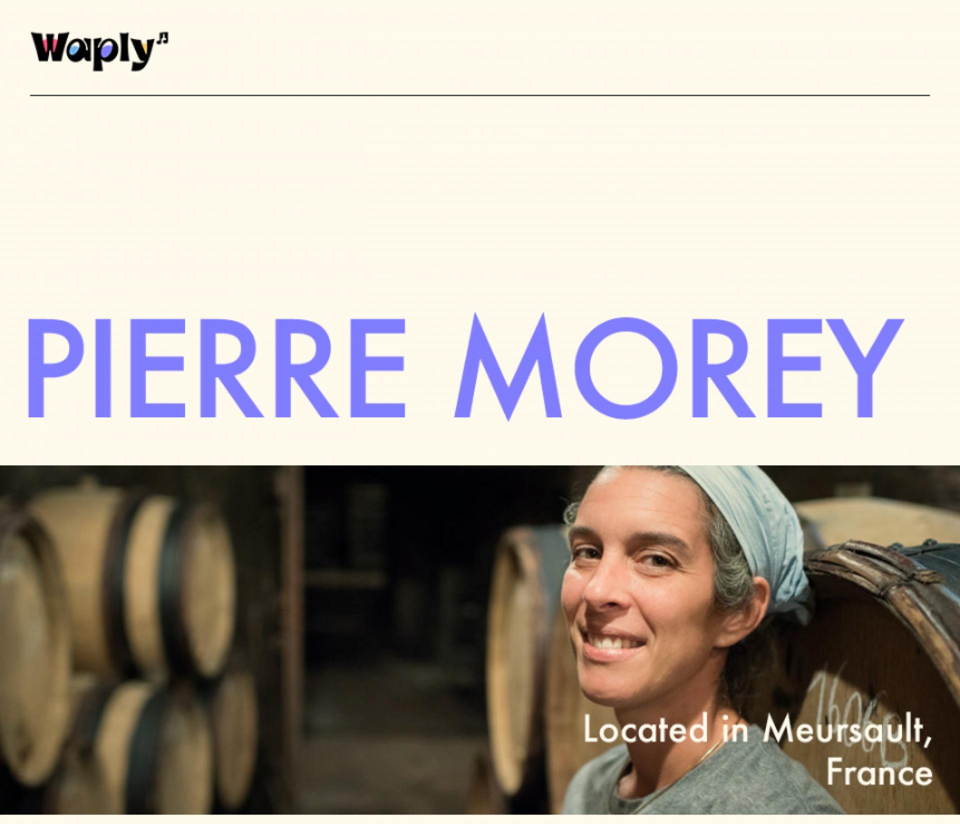  이 이미지는 "Pierre Morey"라는 텍스트와 함께, 프랑스 뫼르소에 위치한 와이너리의 대표적 인물을 보여주고 있습니다. 인물은 와인 배럴 앞에 서있고, 와이너리의 상징적인 장소에서 카메라를 향해 미소 짓고 있는 여성의 모습이 보입니다. 이 와인 양조장은 질감이 느껴지는 돌과 목재 요소로 이루어진 전통적인 건축 양식을 띠고 있어, 장인정신과 역사가 깊은 와인 생산 전통을 상징하는 듯한 분위기를 풍깁니다.