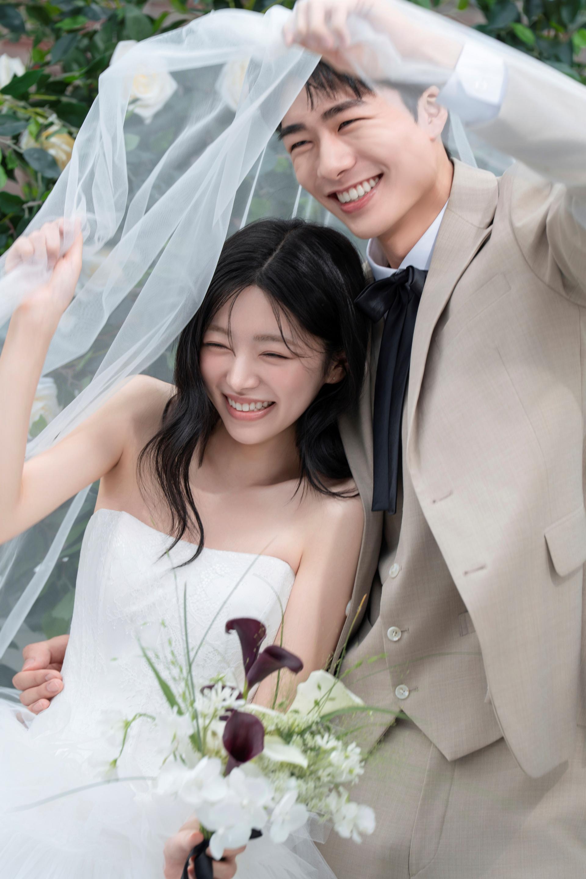 로렌하우스 웨딩 스튜디오 야외 정원 배경에서 베일을 함께 쓰고 환하게 웃고 있는 신랑 신부의 커플 웨딩 사진