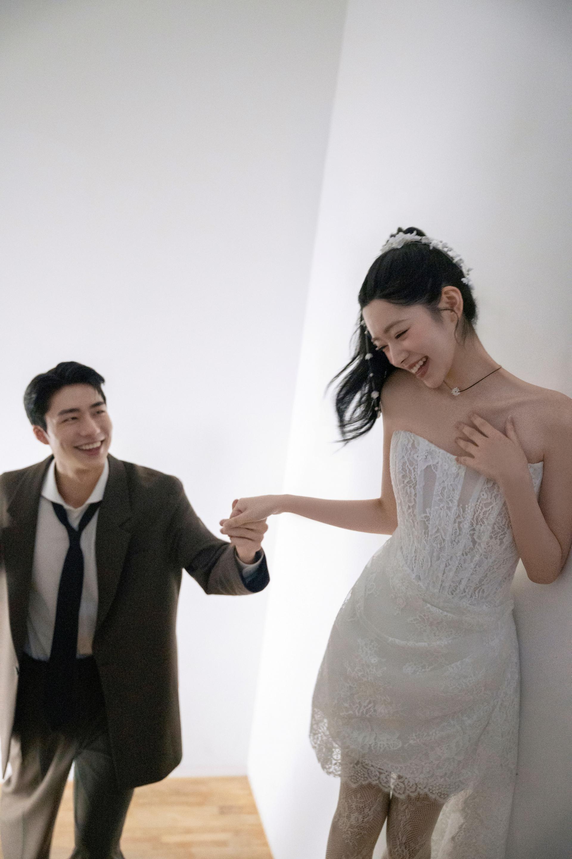 로렌하우스 웨딩 스튜디오 레이스 웨딩드레스를 입은 신부의 손을 잡고 미소 짓는 신랑의 모습을 담은 커플 웨딩 사진
