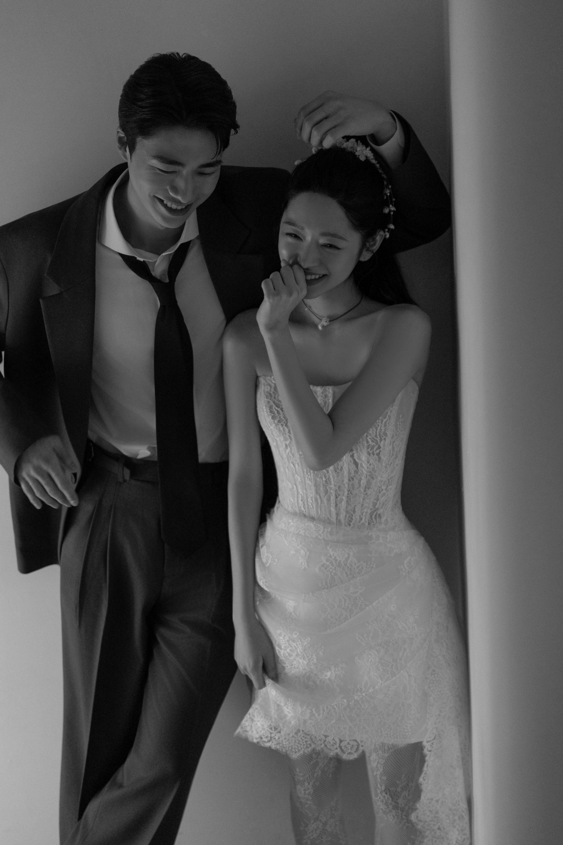 로렌하우스 웨딩 스튜디오 레이스 웨딩드레스를 입은 신부와 수트를 입은 신랑이 환하게 웃고 있는 모습을 흑백 감성으로 담은 웨딩 사진