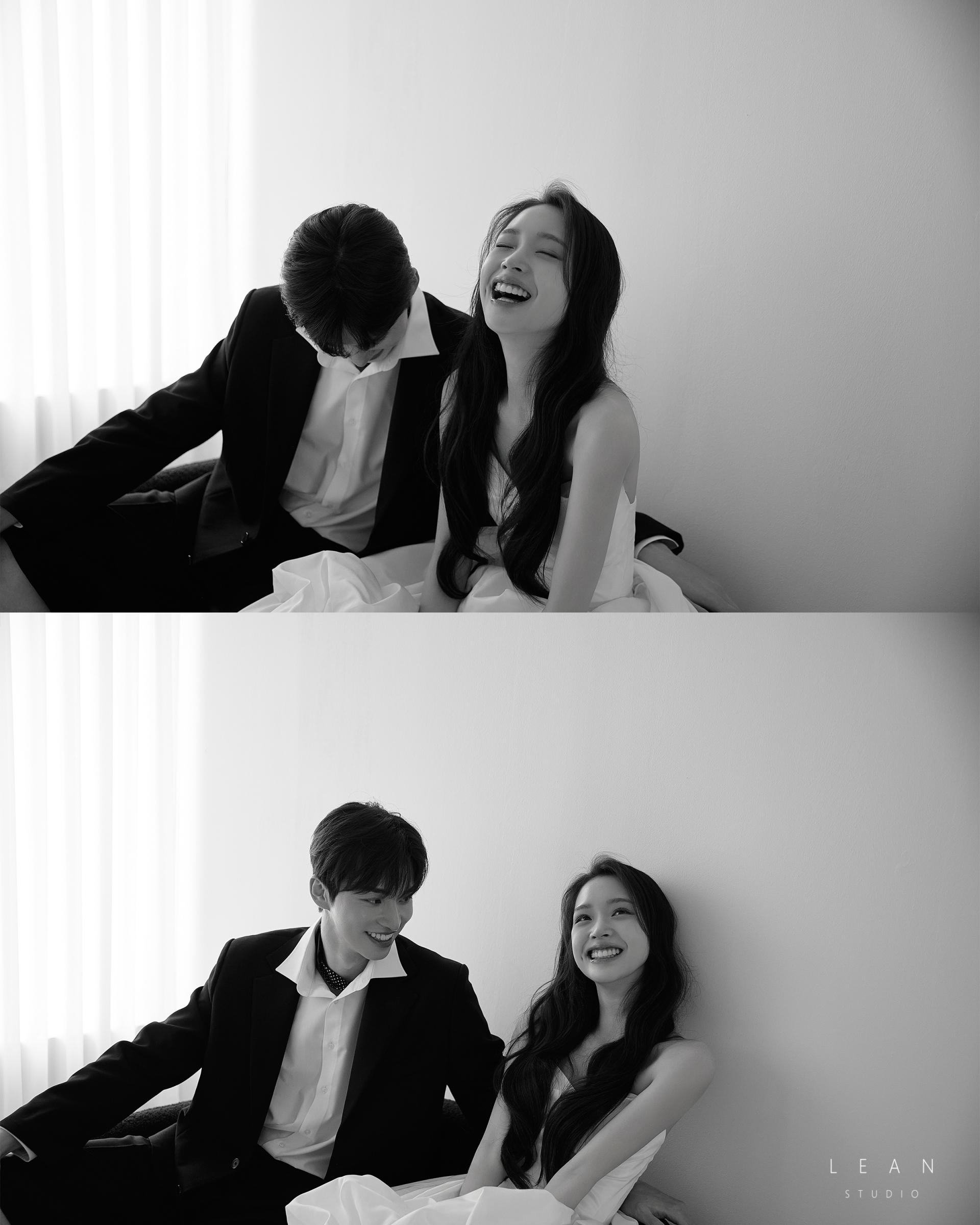 르안 스튜디오 웨딩 스튜디오 화이트 플라워 부케를 품에 안고 블랙 수트를 입은 신랑이 바닥에 앉아 시선을 옆으로 향한 감성적인 신랑 단독 웨딩 촬영컷