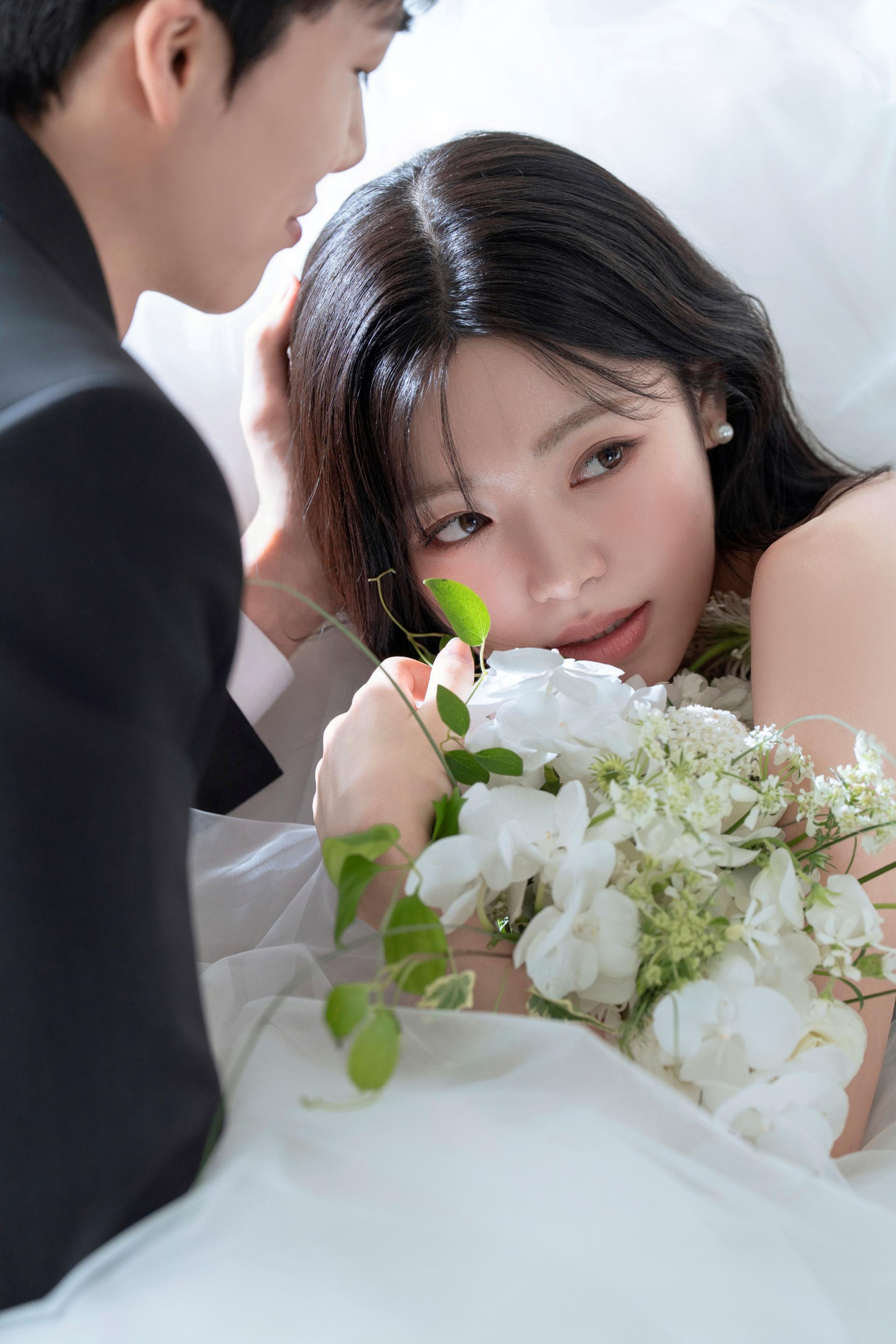 로렌하우스 웨딩 스튜디오 화이트 부케를 든 신부의 얼굴을 신랑이 다정하게 감싸 안은 클로즈업 웨딩 사진