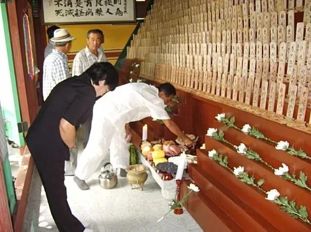 Han Jeong-soon, the president of the Korean Society for the Second Generation Patients Atomic Bombs, pays her respects at a memorial space featuring plaques with the names of Koreans who died while suffering the aftereffects of the US atomic bombings of Japan, located at a welfare center for Korean A-bomb victims in Hapcheon, South Gyeongsang Province. (Choi Sang-won/Hankyoreh)