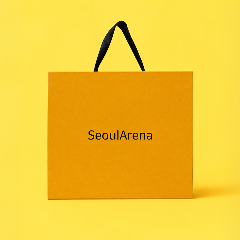전면 중앙에 깔끔한 'SeoulArena' 로고가 배치되고 블랙 쇼핑백 끈 손잡이가 결합된 선명한 옐로우 컬러의 디자인 그립 슬리브 박스 외관 뷰.