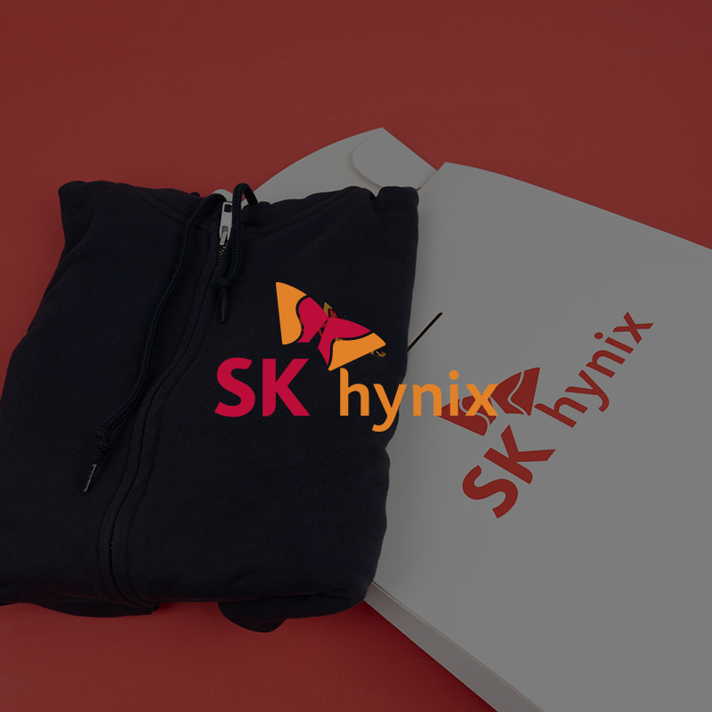 레드 배경 위에서 돋보이는 SK하이닉스 후드집업과 전용 패키지 구성입니다. 기업의 핵심 컬러를 활용한 강렬한 연출이 특징입니다.