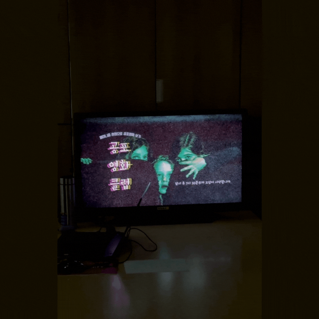 공포영화클럽 소모임의 시작이 저녁 7시 30분부터라는 이미지가 띄워진 모니터. 주위는 어둡다.