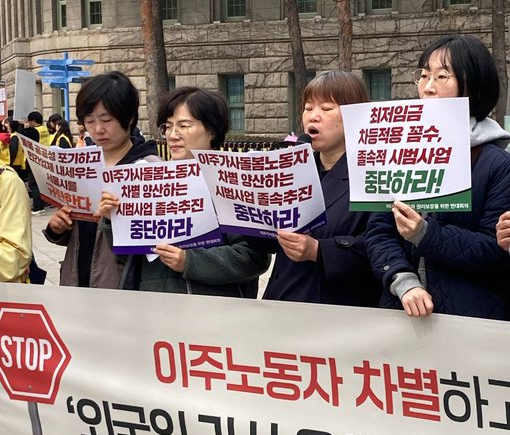 갈색 머리에 여성이 피켓과 마이크를 들고 발언하고 있다.