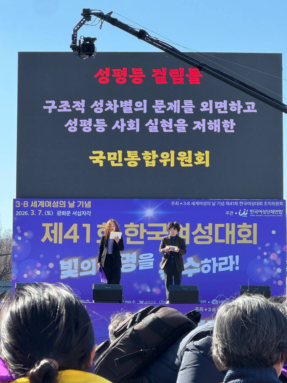 사진 24. 올해의 성평등 걸림돌을 무대에서 발표하고 있다. 국민통합위원회가 스크린에 게시되어있다.