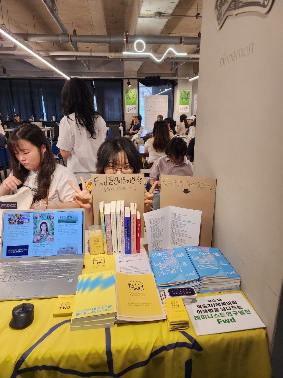 부스 앞에서 양손 브이를 하고 웃고 있는 Fwd 부스 운영자들의 모습