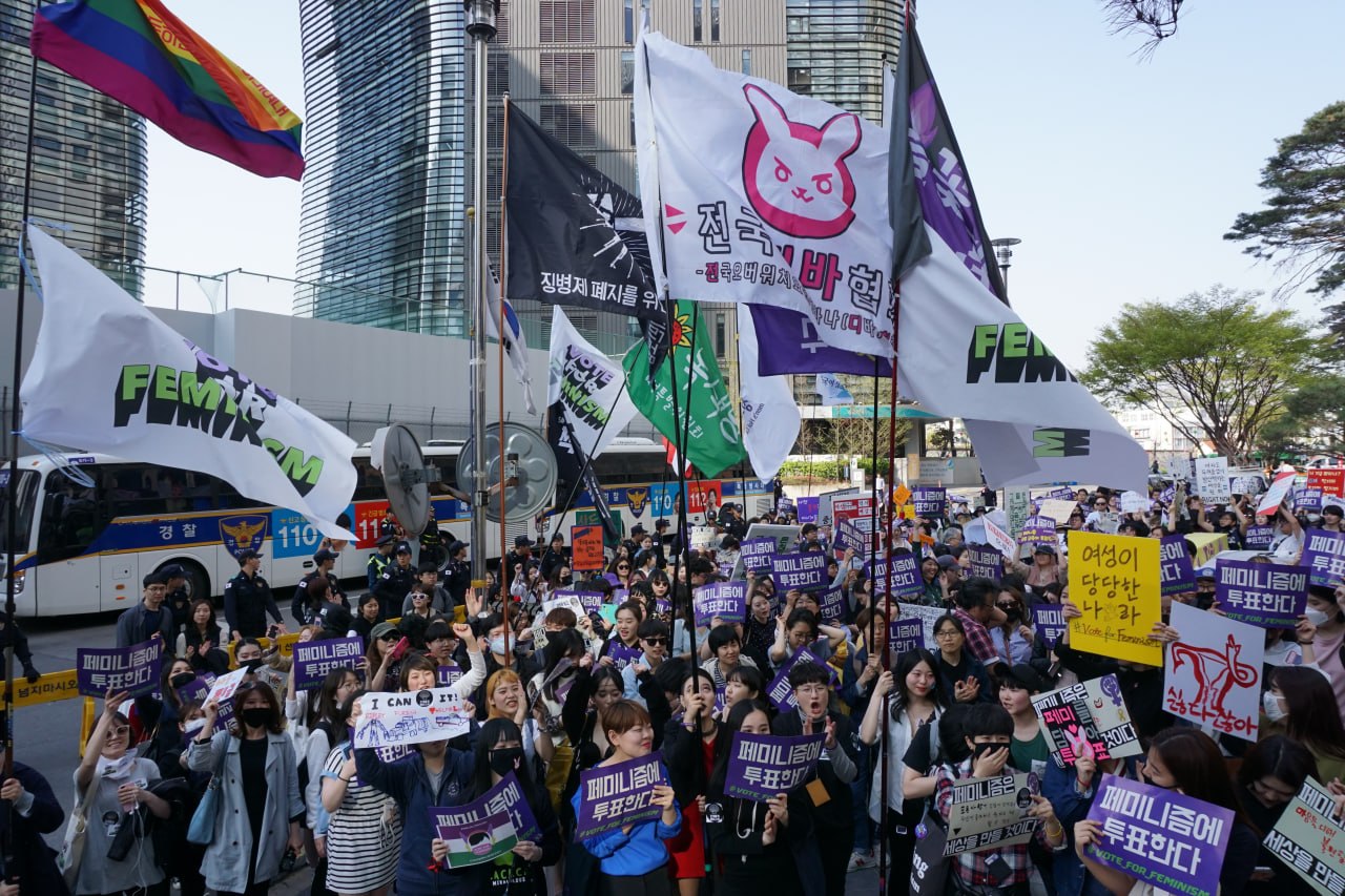 페미니즘에 투표한다 캠페인에서 깃발을 들고 행진하고 있는 사람들의 모습