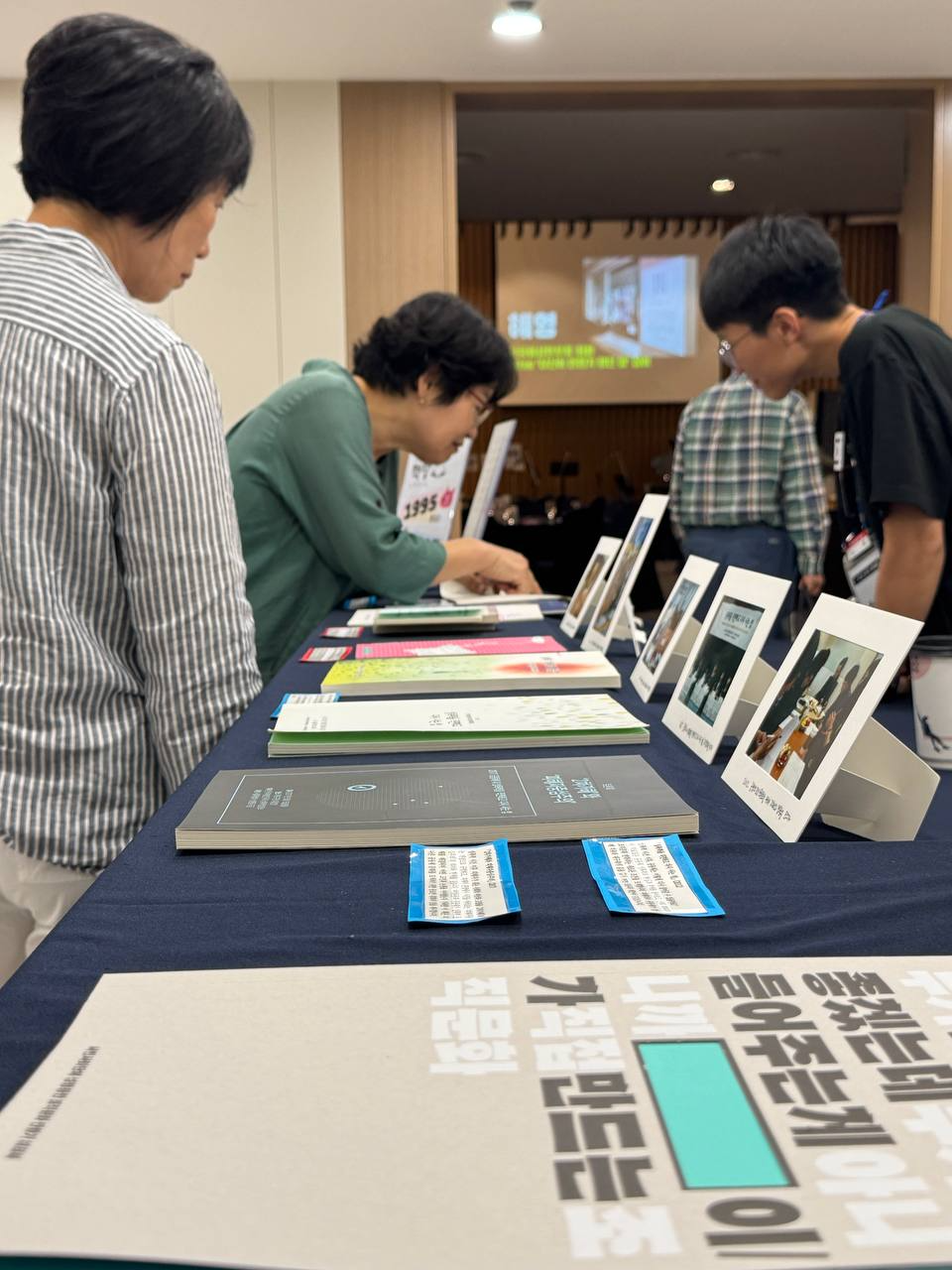 두 명의 다른 사람이 테이블 위에 놓인 책자들을 보고 있는 모습. 