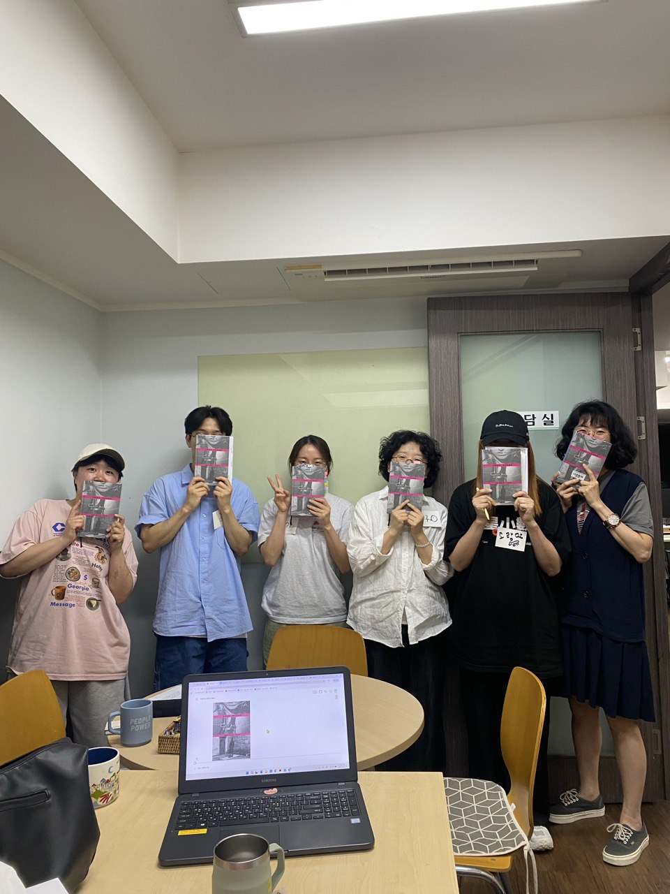 6명의 회원 및 활동가가 친애하는 개자식에게를 들고 카메라를 바라보고 있다