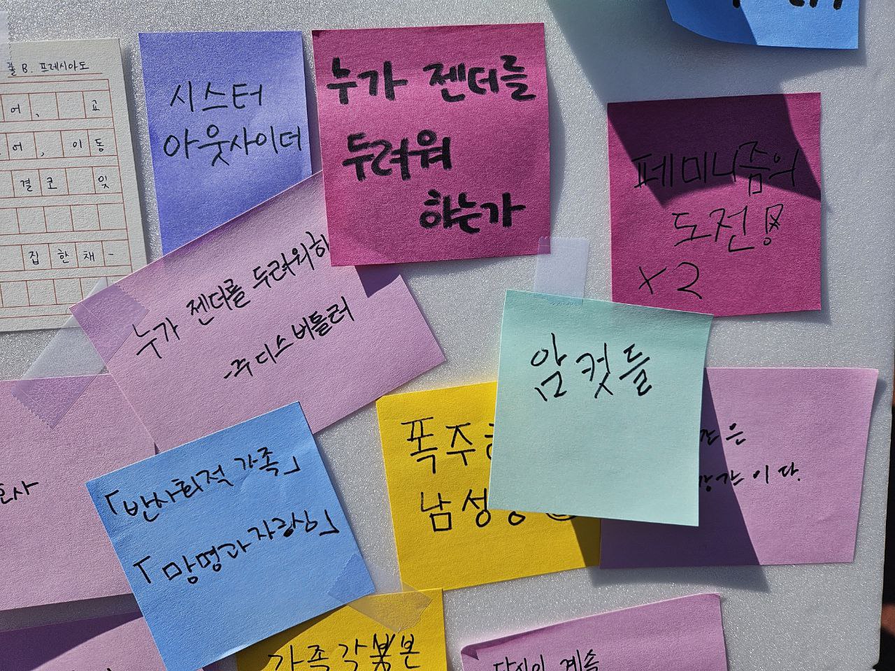 사진 12. 읽는 페미니스트 판넬 위에 적힌 추천 책들. 누가 젠더를 두려워 하는가, 시스터 아웃사이더, 암컷들, 폭주하는 남성성, 욕구들, 레이디 크레딧 등 다양한 페미니즘 책들이 쓰여있다.