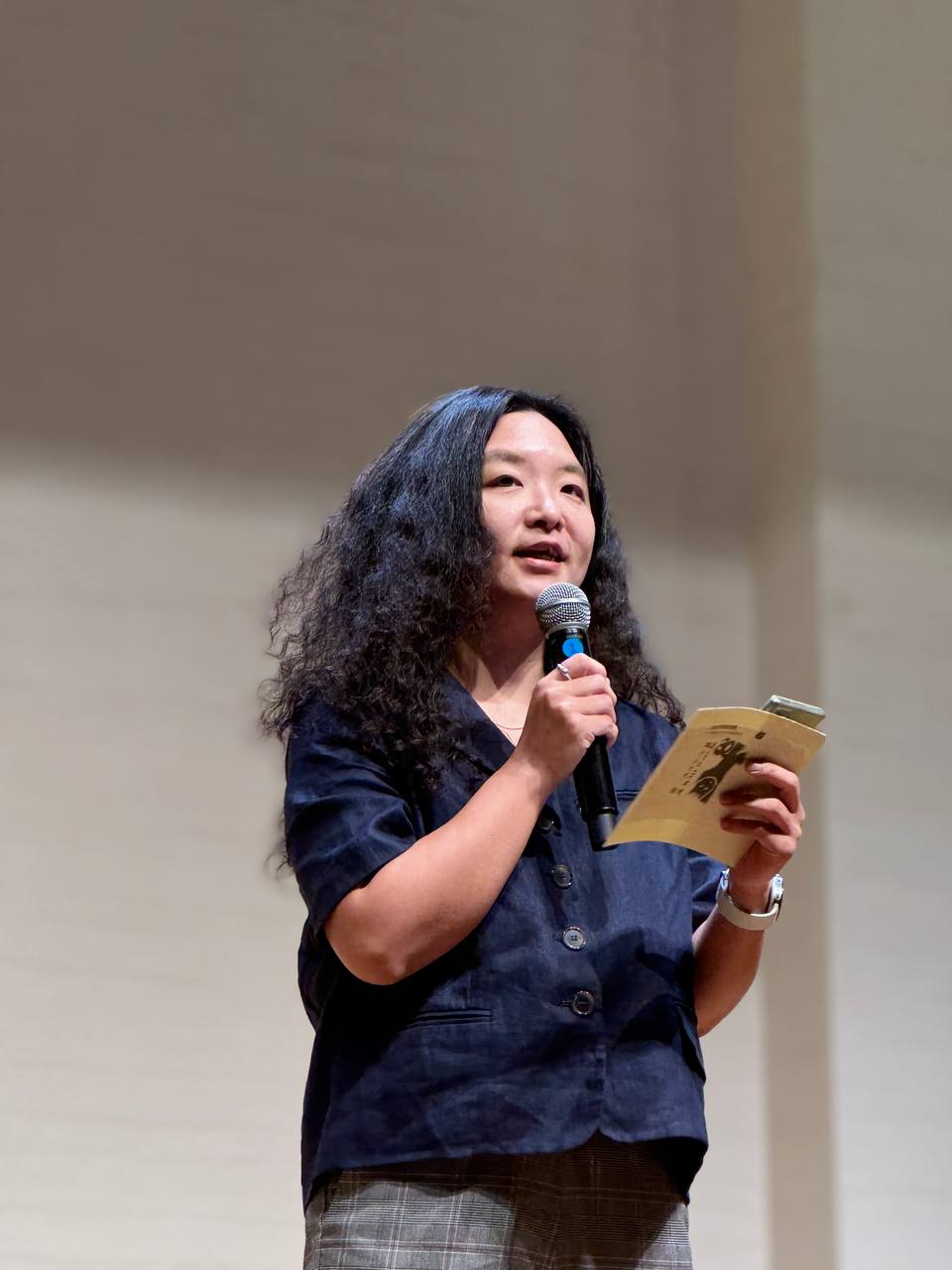 최김하나 전 활동가의 발표 모습. 긴 머리에 푸른색 옷을 입고, 마이크와 노트를 들고 청중석을 바라보며 미소띈 얼굴로 뭔가 말하고 있다. 