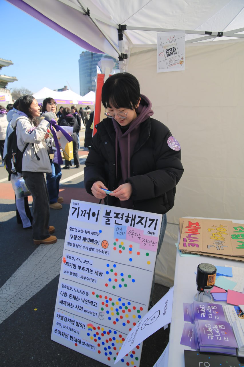 사진 4. 민우회 활동가 다혜가 기꺼이 불편해지기 설문조사를 위한 판넬을 들고 있다. 문제적 장면 4가지에 골고루 스티커가 붙여져있다.