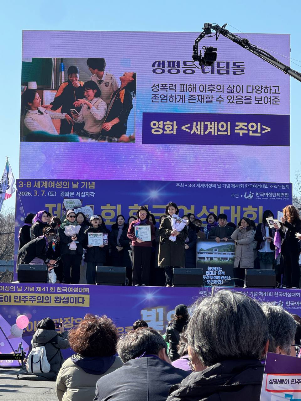 사진 31. 무대에서 올해의 성평등 디딤돌을 발표하고 있다. 수상자 이름 영화 <세계의 주인>이 무대 스크린에 게시되어있다.