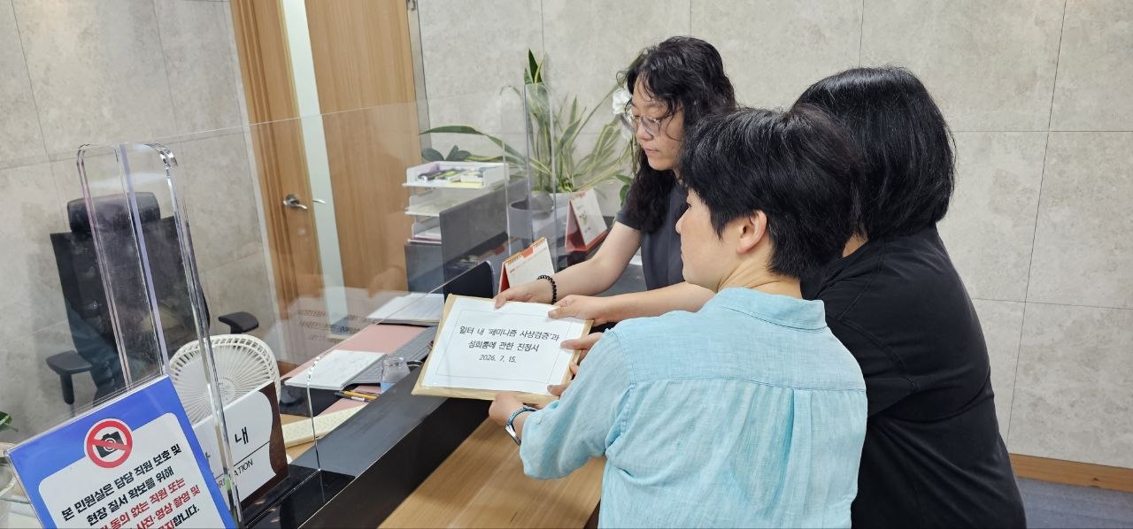 세 명이 '일터 내 페미니즘 사상검증과 성희롱에 관한 진정서'라고 쓰여진 서류봉투를 제출하고 있다.