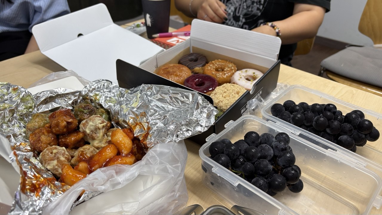 도넛츠, 닭강정, 포도가 테이블 위에 펼쳐져있다.