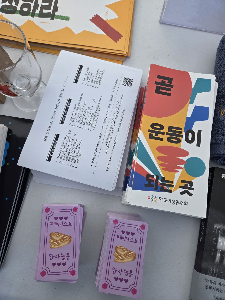 사진 20. 민우회 리플렛과 페미니스트 만사형통 부적 스티커가 부스 테이블에 놓여있다.