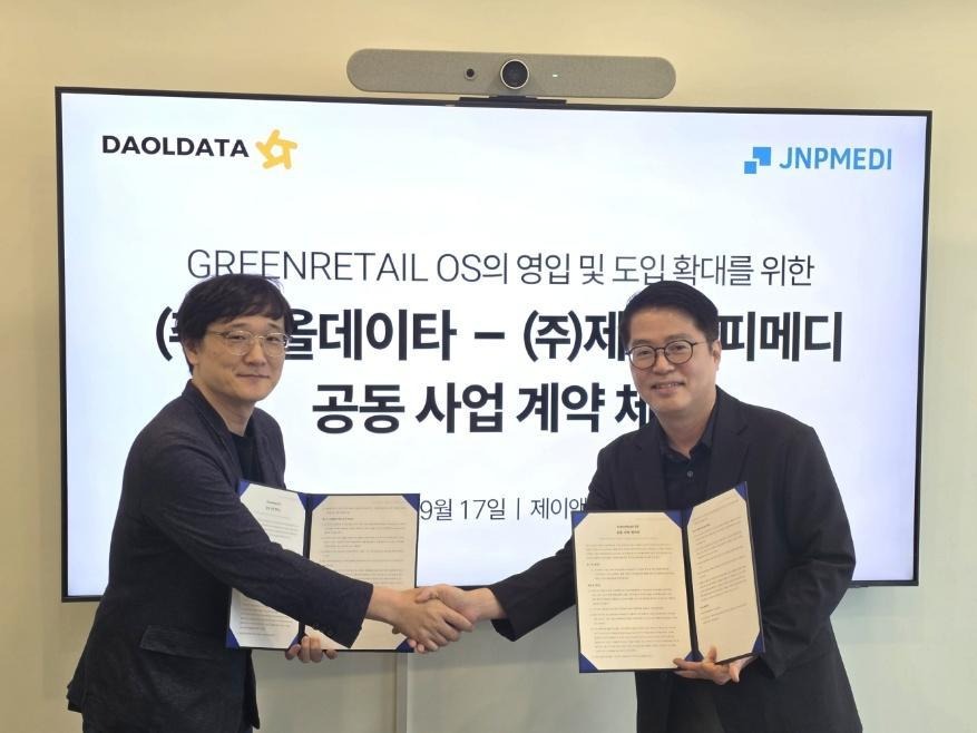 The image shows two people shaking hands while holding documents in front of a large digital screen displaying a joint contract.  AI 생성 콘텐츠는 정확하지 않을 수 있습니다.