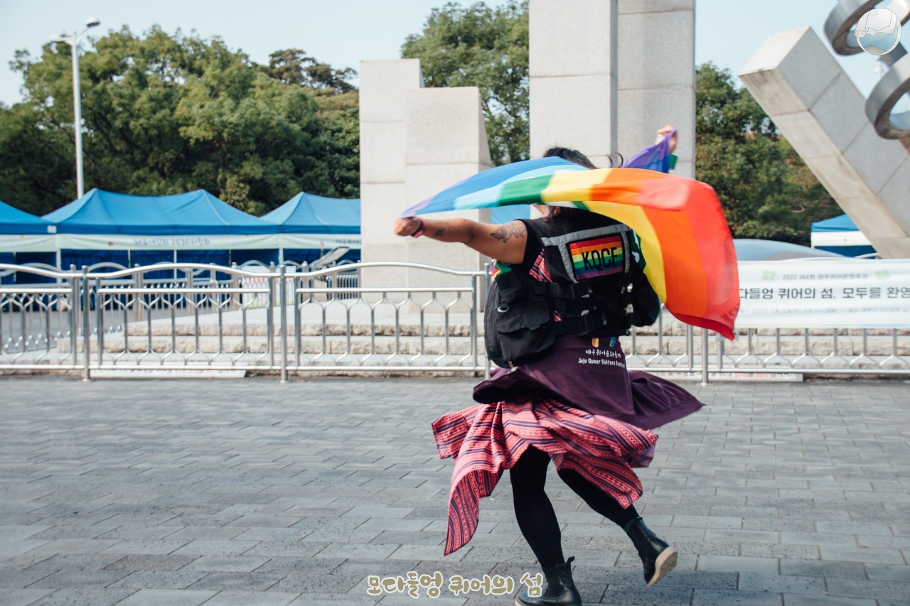 무지개 깃발을 뒤로 넓게 들고 제자리에서 돌고 있는 혜영의 뒷모습.