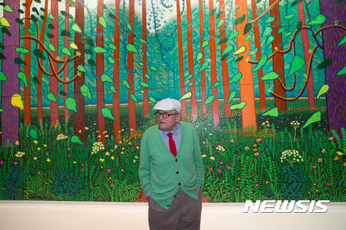 【파리=AP/뉴시스】영국 화가 데이비드 호크니가 26일(현지시간) 프랑스 파리의 퐁피두센터에 기증한 '이스트 요크셔 월드게이트에 도착한 봄(The Arrival of Spring in Woldgate, East Yorkshire)'앞에서 포즈를 취하고 있다. 2011년작인 이 그림은 32개의 패널로 이뤄져 있으며, 높이는 약 3m 길이는 약 10m에 이르는 대작이다.
