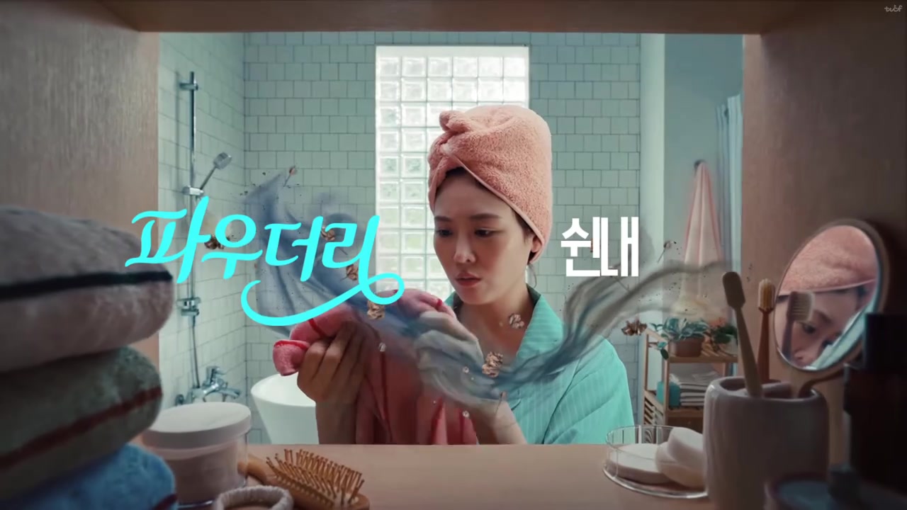욕실에서 머리에 분홍 수건을 두른 인물이 수건 냄새를 맡으며 파우더리 쉰내 자막이 떠 있는 장면
