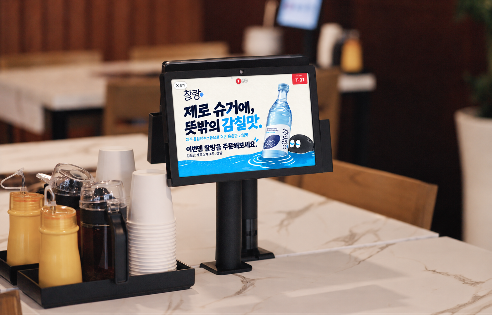 매장 내 맛의 제안과 주문 요청을 연결한 티오더 적용안. 배경사진 출처: 티오더 공식 광고 상품 소개. 제품·캐릭터·로고 참조: 찰랑 공식 홈페이지. 화면 내 광고·목업 편집: 애드타입 비공식 제안. 실제 찰랑·티오더 제휴 또는 송출 사례가 아닙니다.